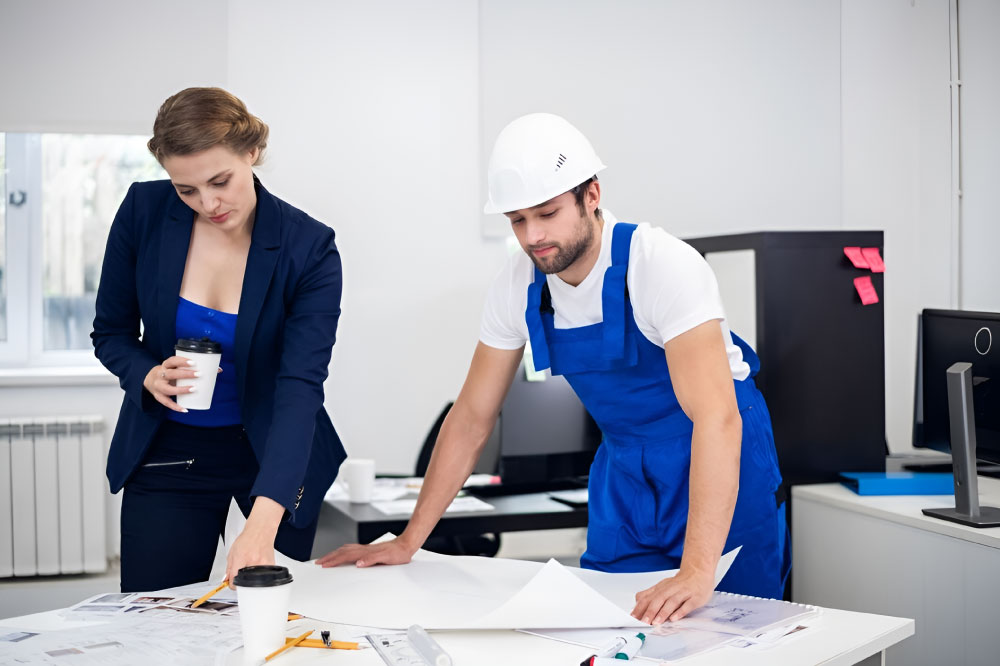 A female engineer and a site worker reviewing blueprints, representing professional Engineering Consultancy in Abu Dhabi.